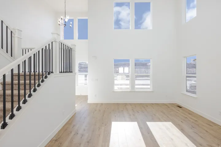 Two-story living area with high ceilings, multiple windows, and light wood-finish flooring