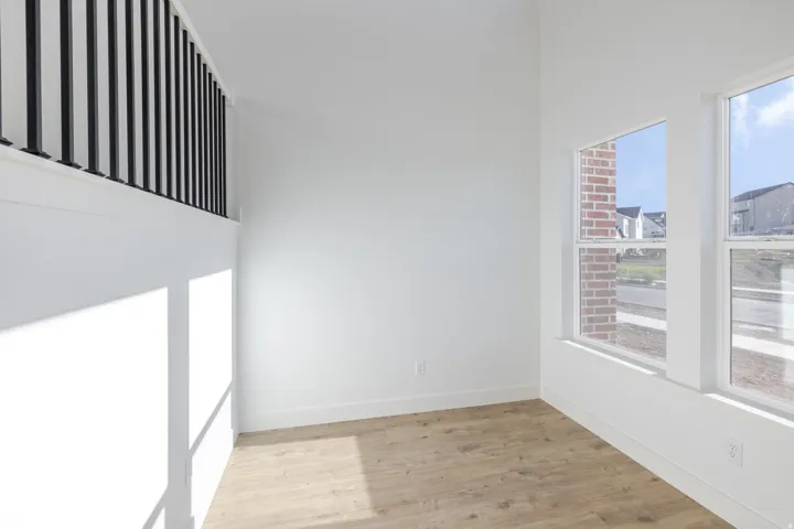Room featuring wood-finish flooring, white baseboards, and bright white walls