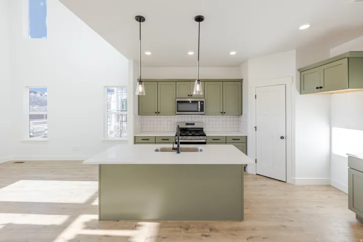 Kitchen island featuring a white countertop and integrated sink, complemented by dual pendant lighting
