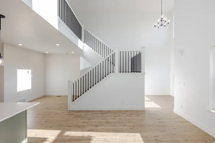 Two-story space featuring a white staircase with black balusters, light wood-finish flooring, recessed lighting, and a modern chandelier