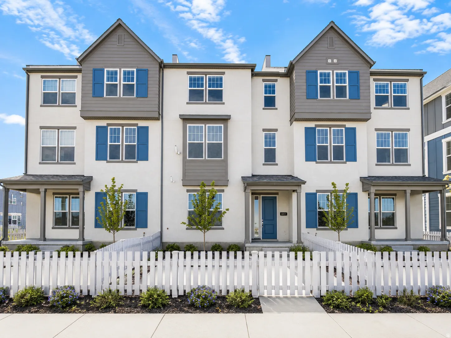 Contemporary multi-story facade featuring light-colored stucco, dark trim, and blue window shutters