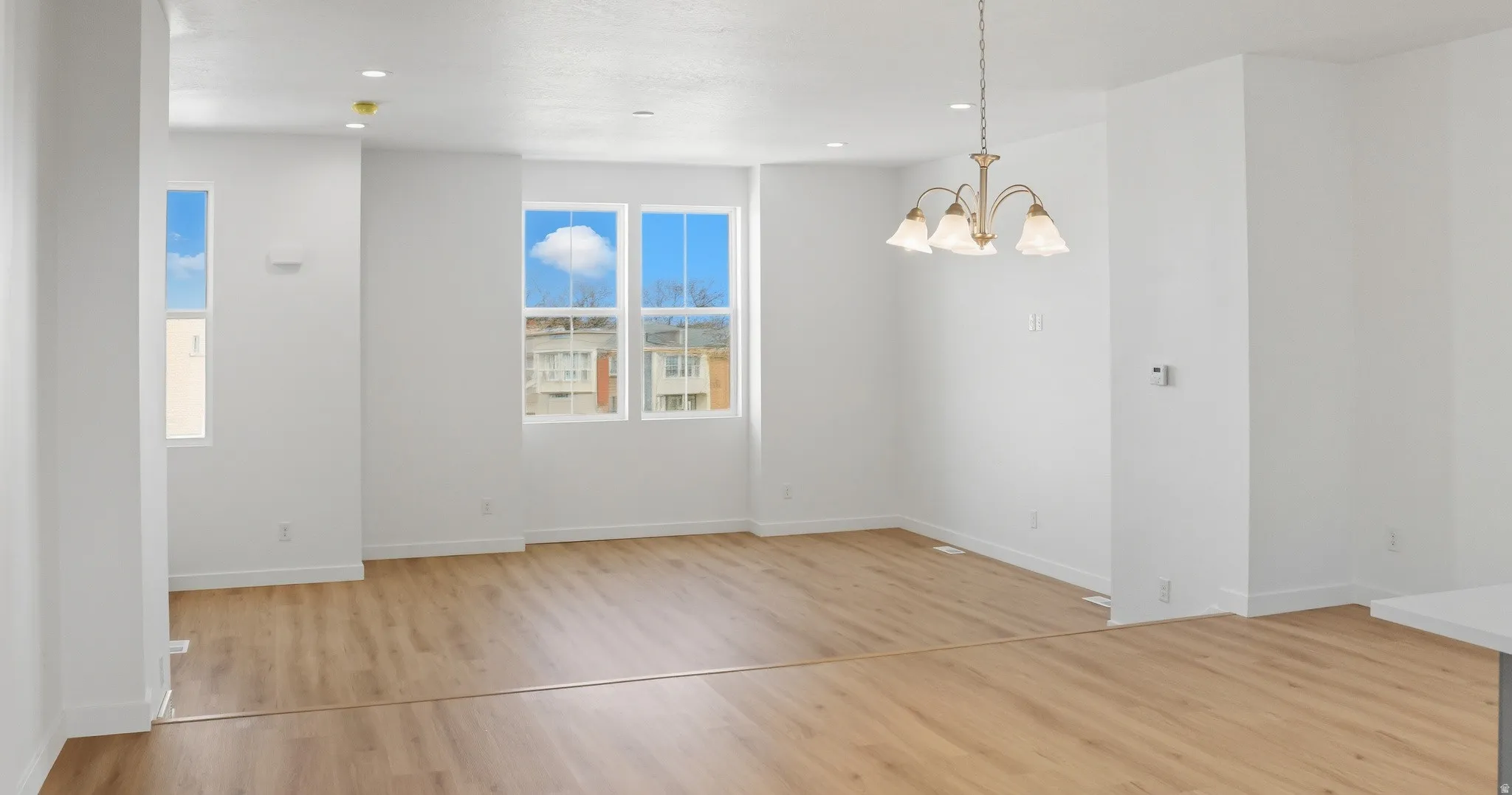 Unfurnished dining area with light wood finished floors, a chandelier, and recessed lighting
