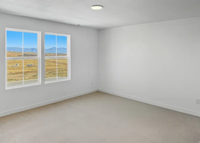 Spare room with a mountain view, a textured ceiling, and light carpet