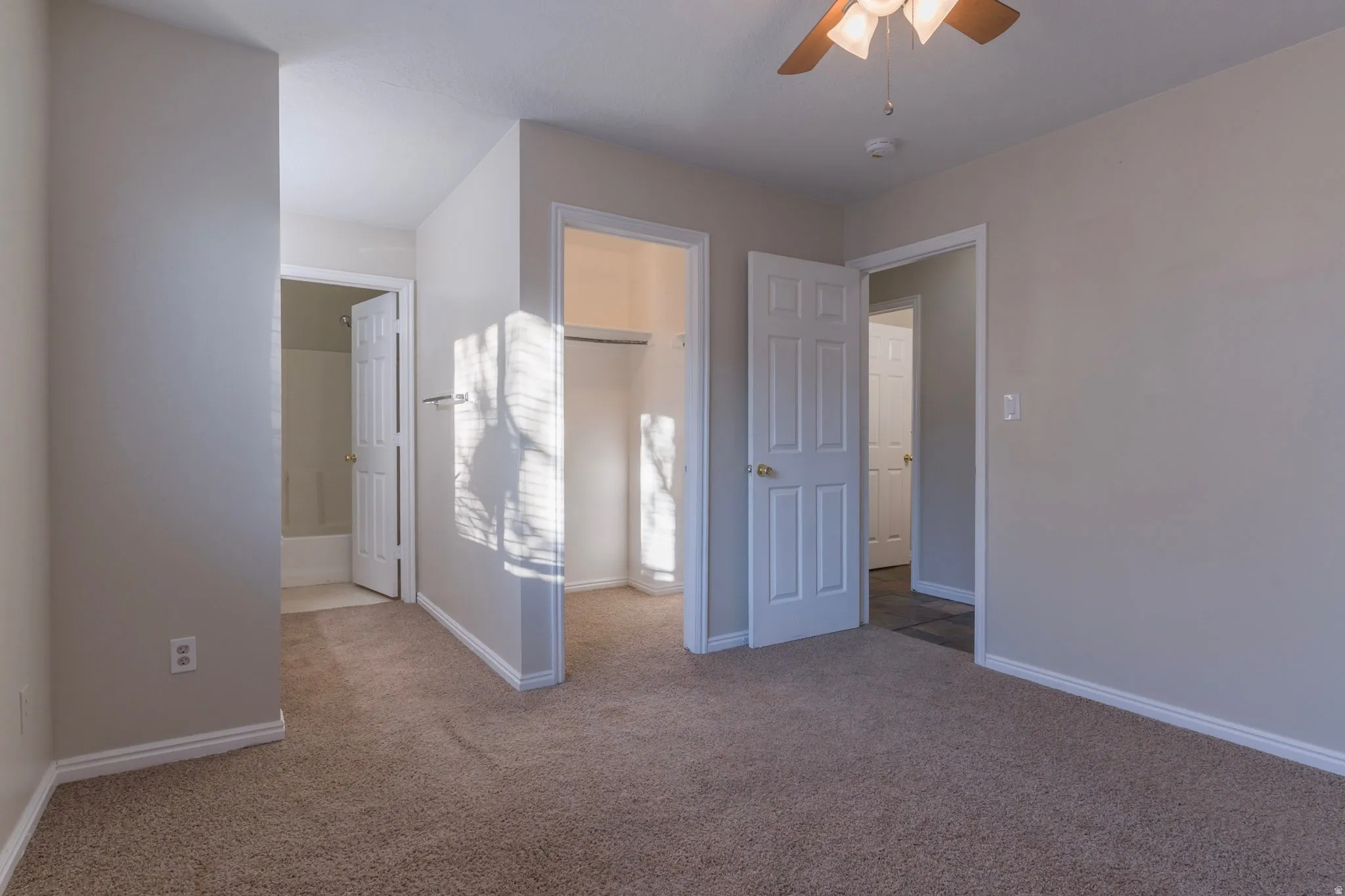 Unfurnished bedroom featuring connected bathroom, carpet floors, and ceiling fan