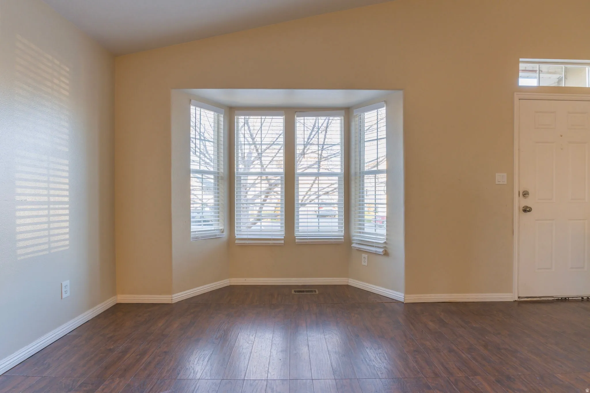 Foyer entrance with healthy amount of natural light, vaulted ceiling, and dark wood-style floors