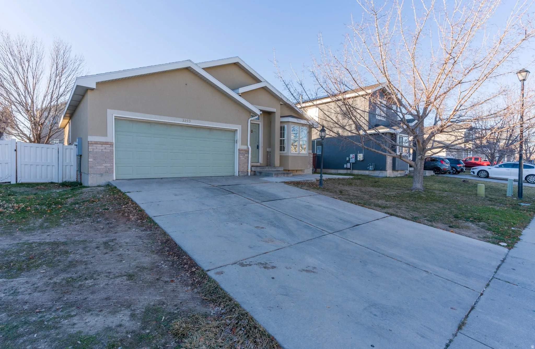 View of front of property with stucco siding, a gate, concrete driveway, an attached garage, and brick siding