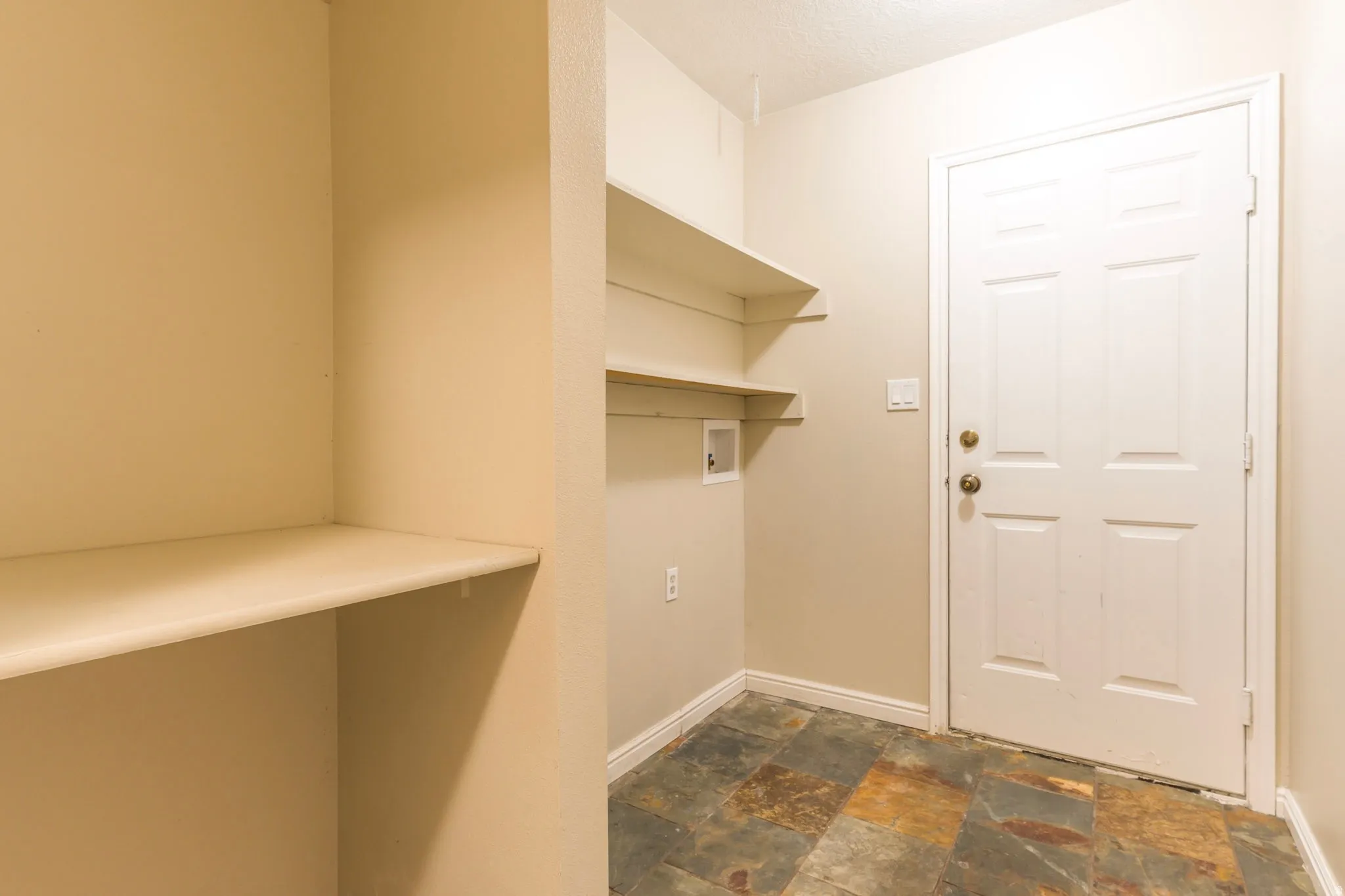 Washroom with stone finish flooring, hookup for a washing machine, and a textured ceiling