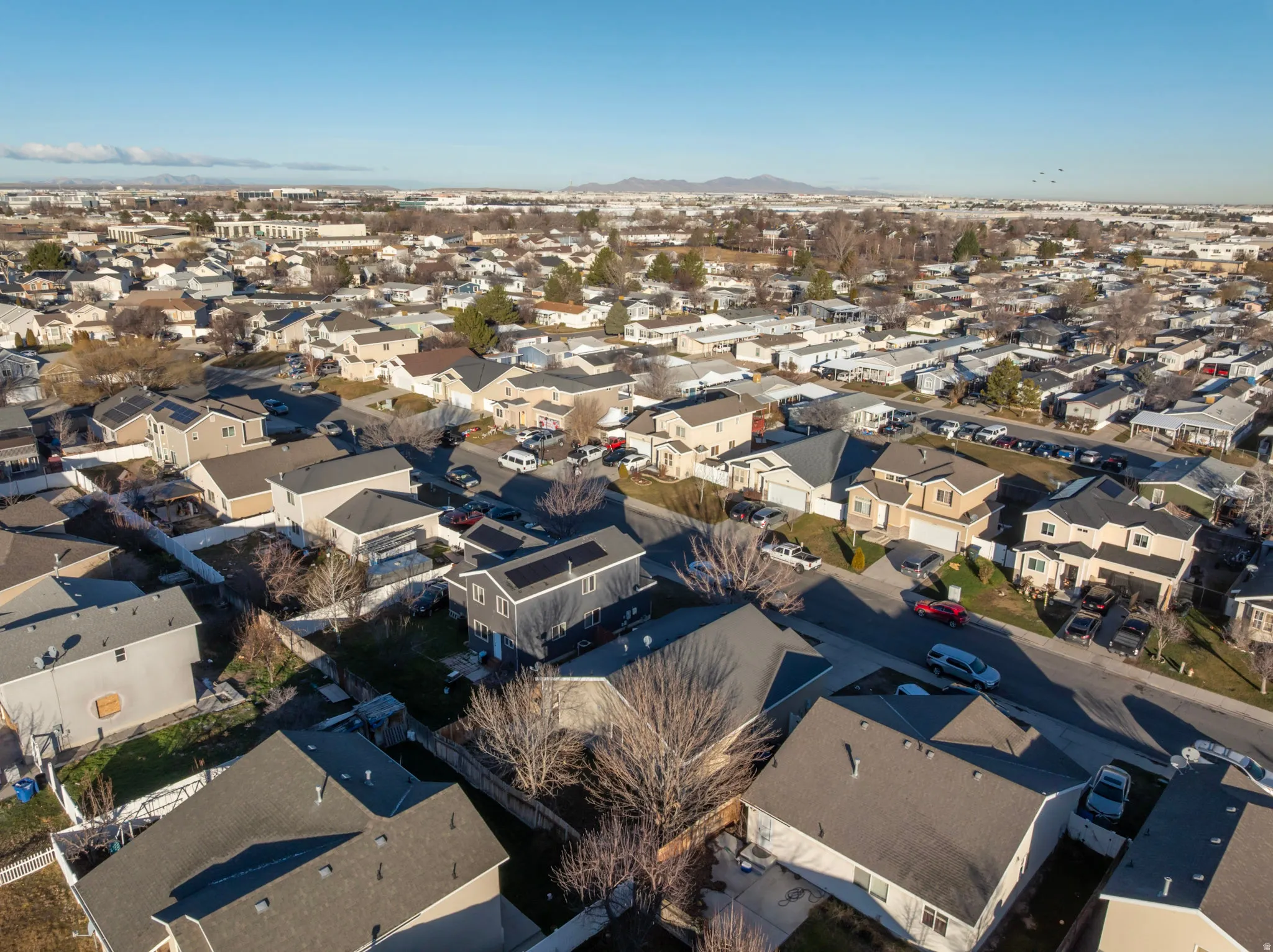 Aerial view of property and surrounding area featuring nearby suburban area and a mountainous background