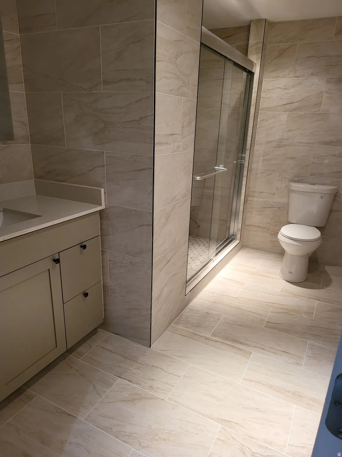 Bathroom featuring tile walls, vanity, and a shower stall