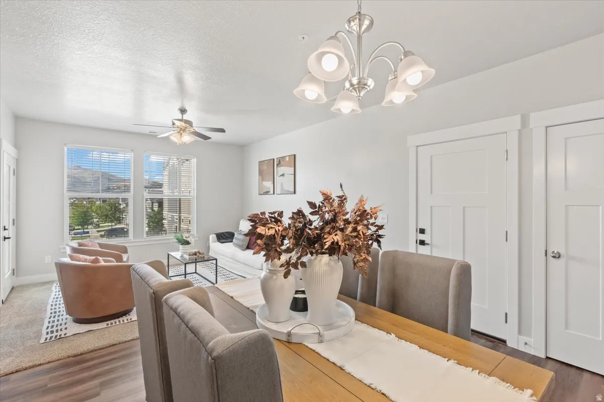 Dining area featuring wood finished floors, a textured ceiling, ceiling fan, and a chandelier
