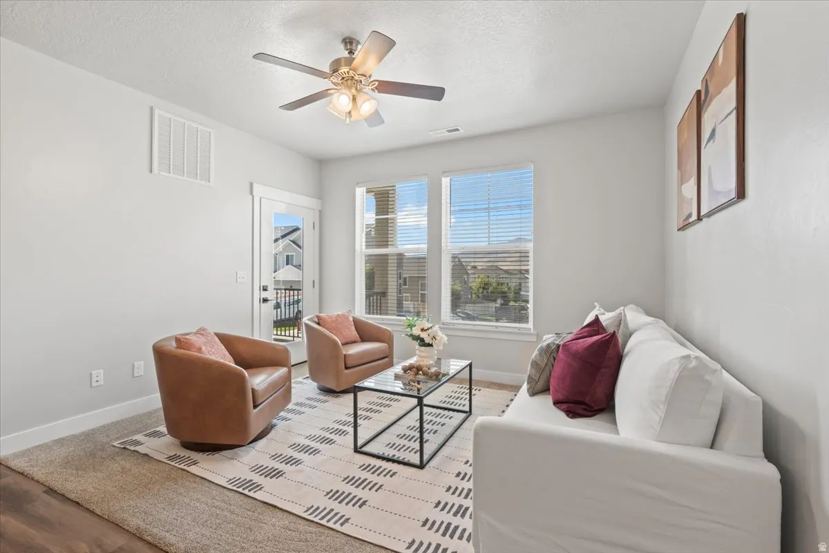 Living room featuring a textured ceiling, wood finished floors, and ceiling fan