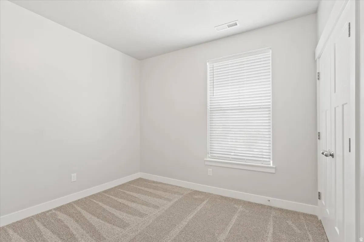 Carpeted spare room featuring baseboards