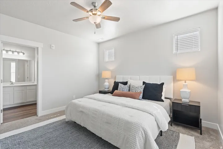Carpeted bedroom featuring ceiling fan and ensuite bathroom
