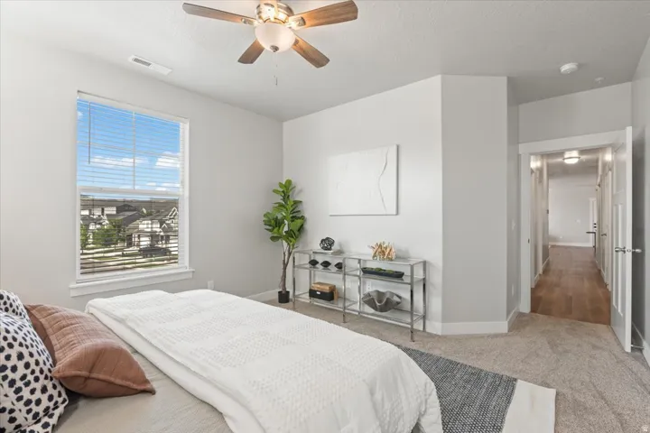 Carpeted bedroom featuring a ceiling fan and a textured ceiling