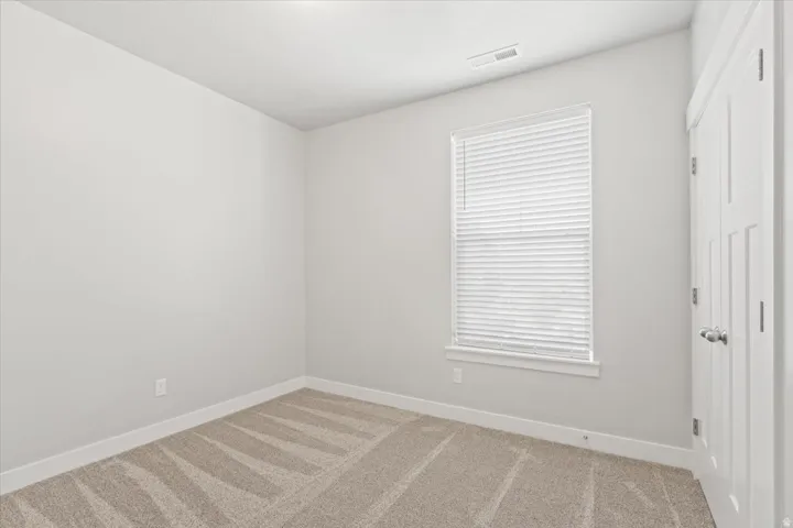 Carpeted spare room featuring baseboards