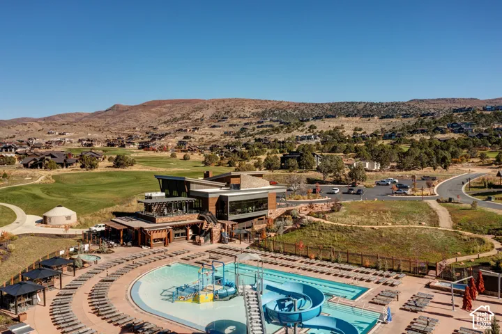 Expansive outdoor pool with water slide, surrounded by multiple cabanas and lounge seating
