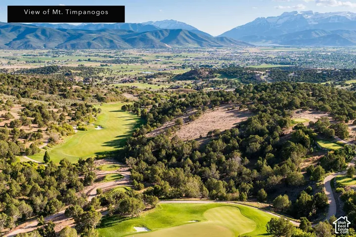 Expansive golf course setting with distant mountain scenery, mature trees, and manicured greens