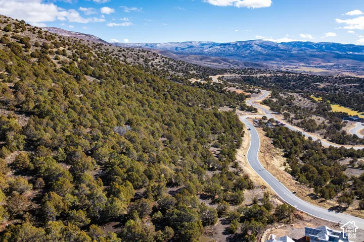 Winding paved road surrounded by varied terrain and distant mountains