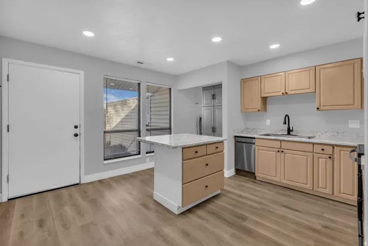 Kitchen featuring light wood finish cabinetry, light stone counters, a center island, light wood-style flooring, and recessed lighting