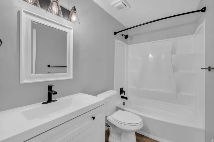 Full bathroom with shower / washtub combination, vanity, and wood finished floors