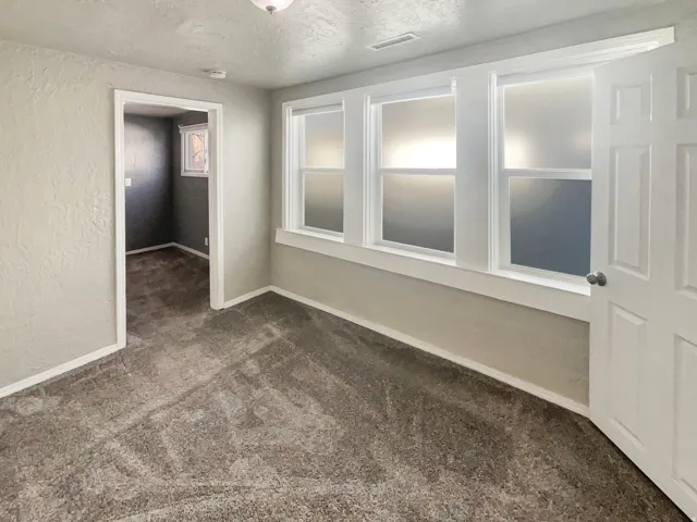 Room featuring three windows with frosted glass, wall-to-wall carpeting, and neutral paint