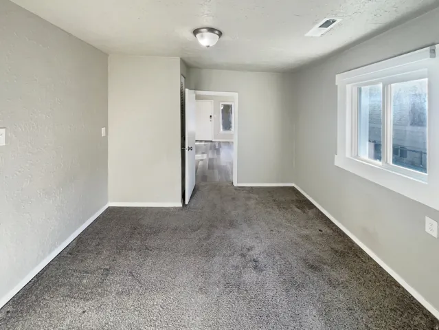Spacious room with gray textured walls and plush gray carpeting
