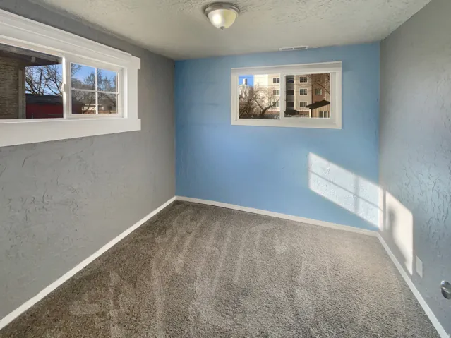 Interior room featuring textured walls in a two-tone paint scheme, two windows with white trim, and a ceiling-mounted light fixture