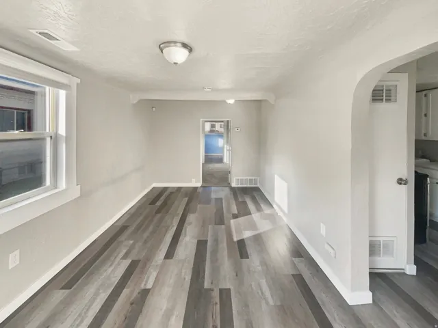 Spacious room featuring wood-finish flooring, light gray wall paint, white trim, and a ceiling-mounted light fixture