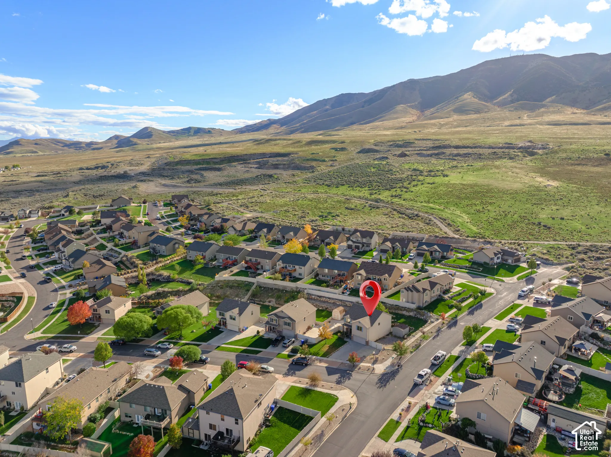 Aerial perspective featuring a multi-story residence with a concrete driveway and mountainous landscape backdrop