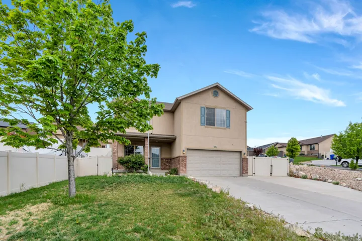 Traditional-style house featuring a gate, brick siding, stucco siding, and concrete driveway