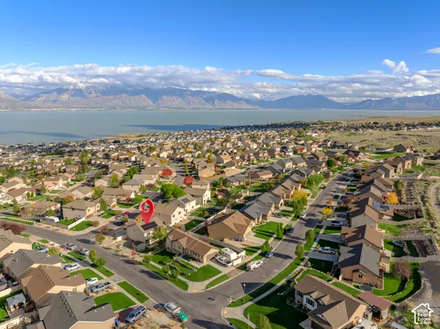 Aerial perspective featuring a residential lot with solar panel installation, mountain range backdrop, and lake scenery