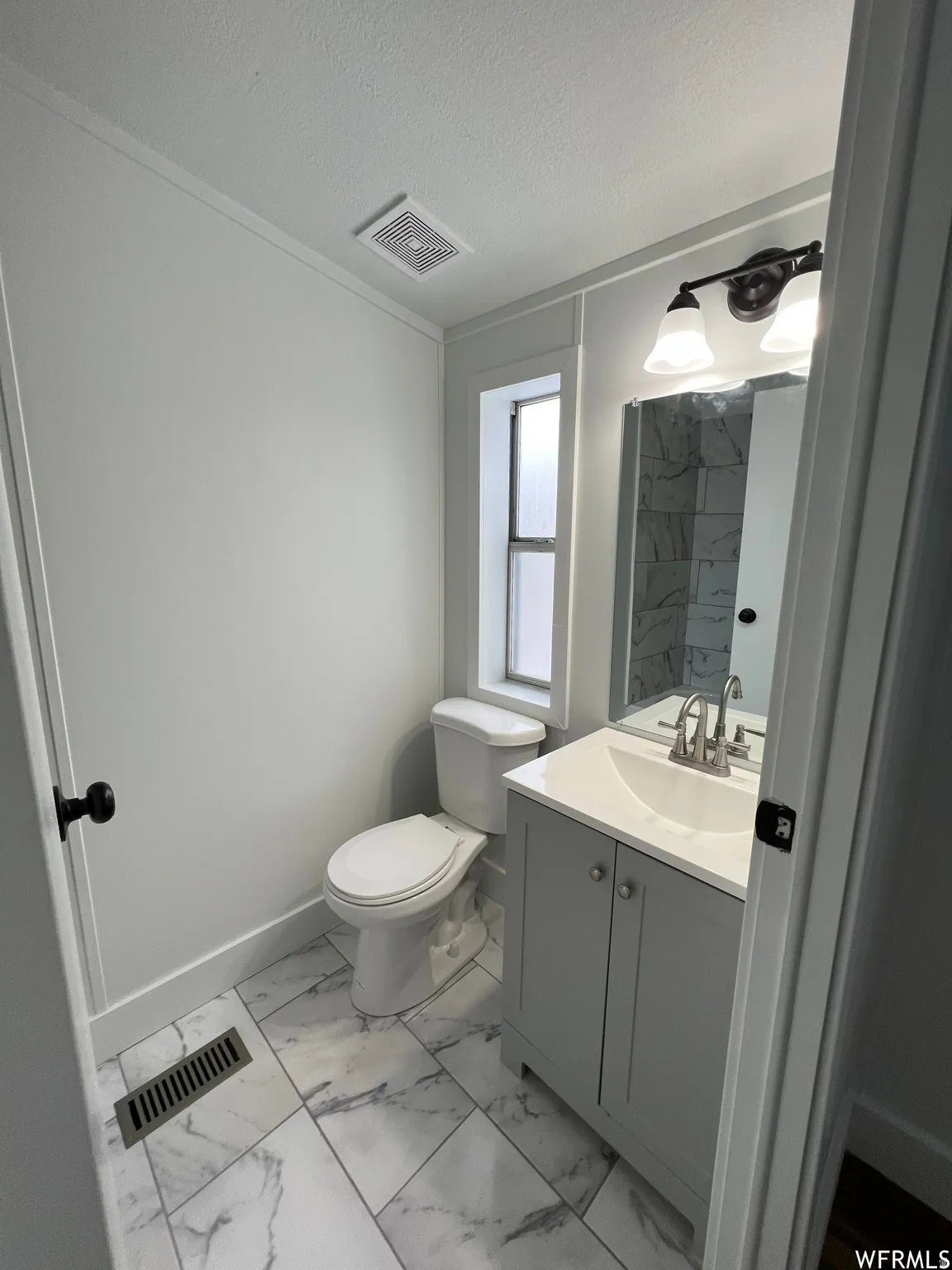 Bathroom with light marble finish flooring, vanity, a textured ceiling, and a marble finish shower