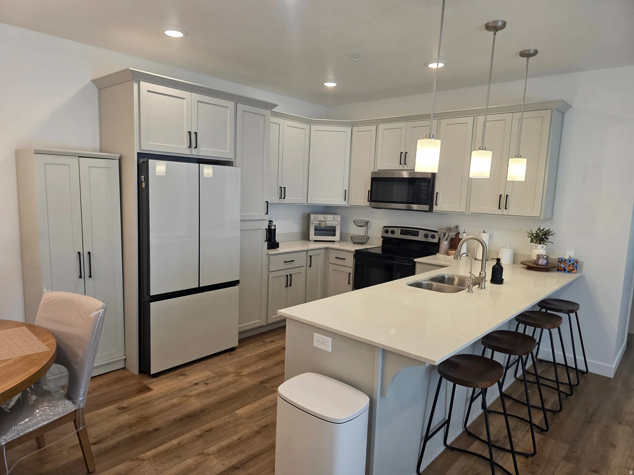 Kitchen featuring pendant lighting, a kitchen breakfast bar, stainless steel appliances, and dark wood-style floors
