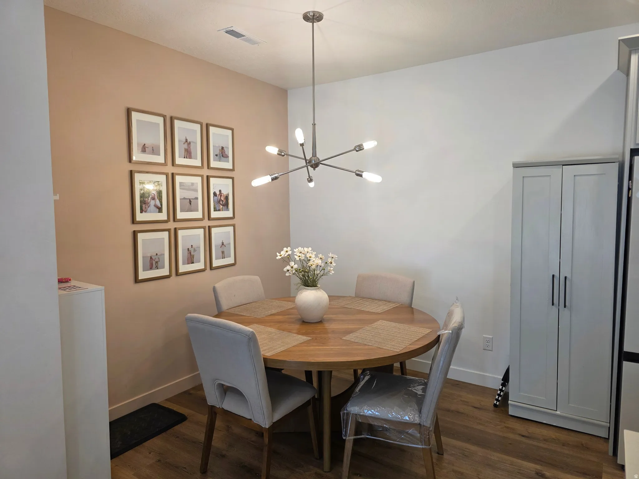 Cute dining area featuring a chandelier and dark wood-style flooring