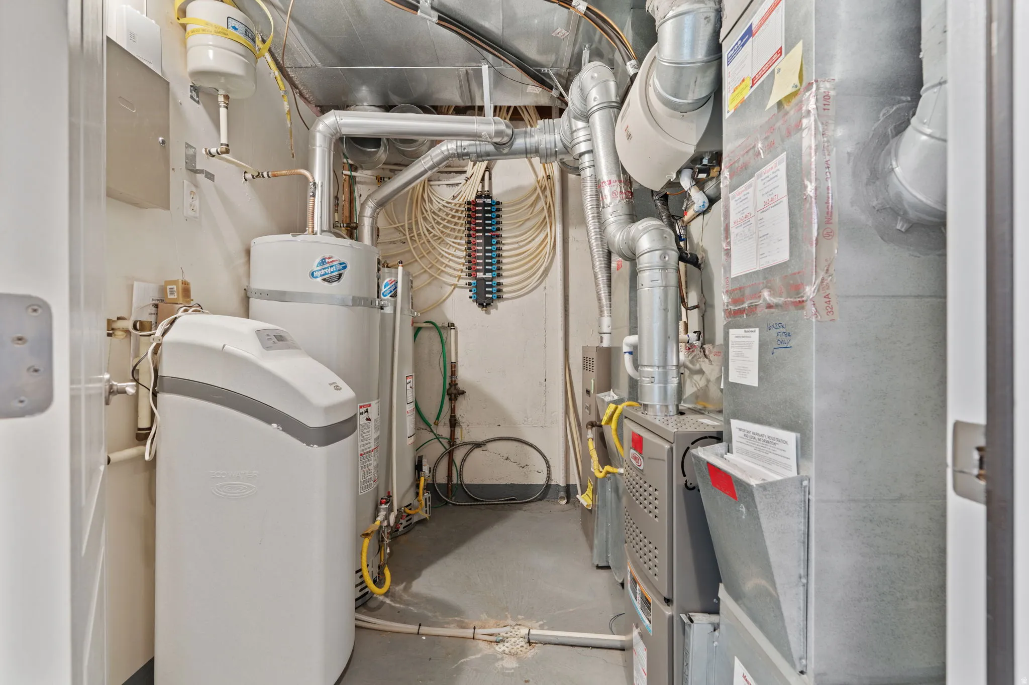 Utility room featuring heating unit, water heater, and gas water heater