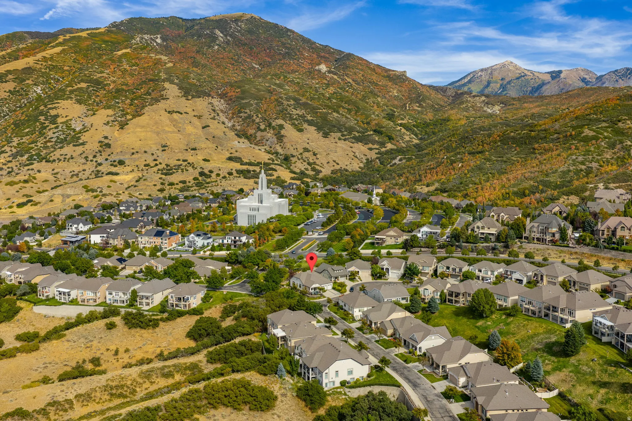Aerial view of property and surrounding area featuring nearby suburban area and a mountain backdrop