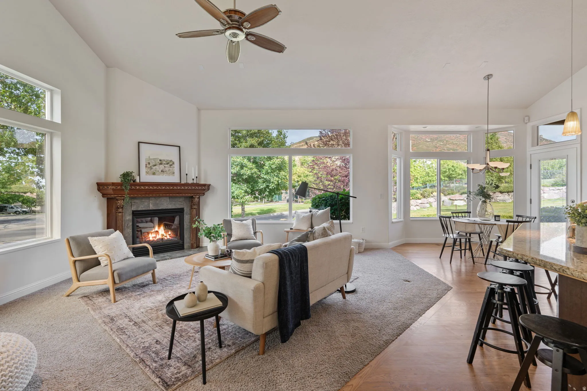 Living area with high vaulted ceiling, a fireplace, and a ceiling fan