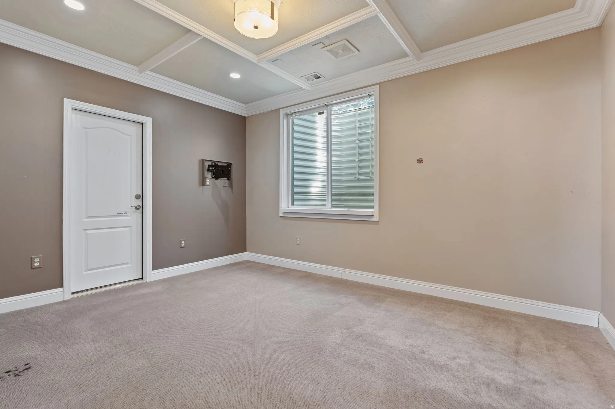 Empty room featuring coffered ceiling, light carpet, crown molding, and beam ceiling