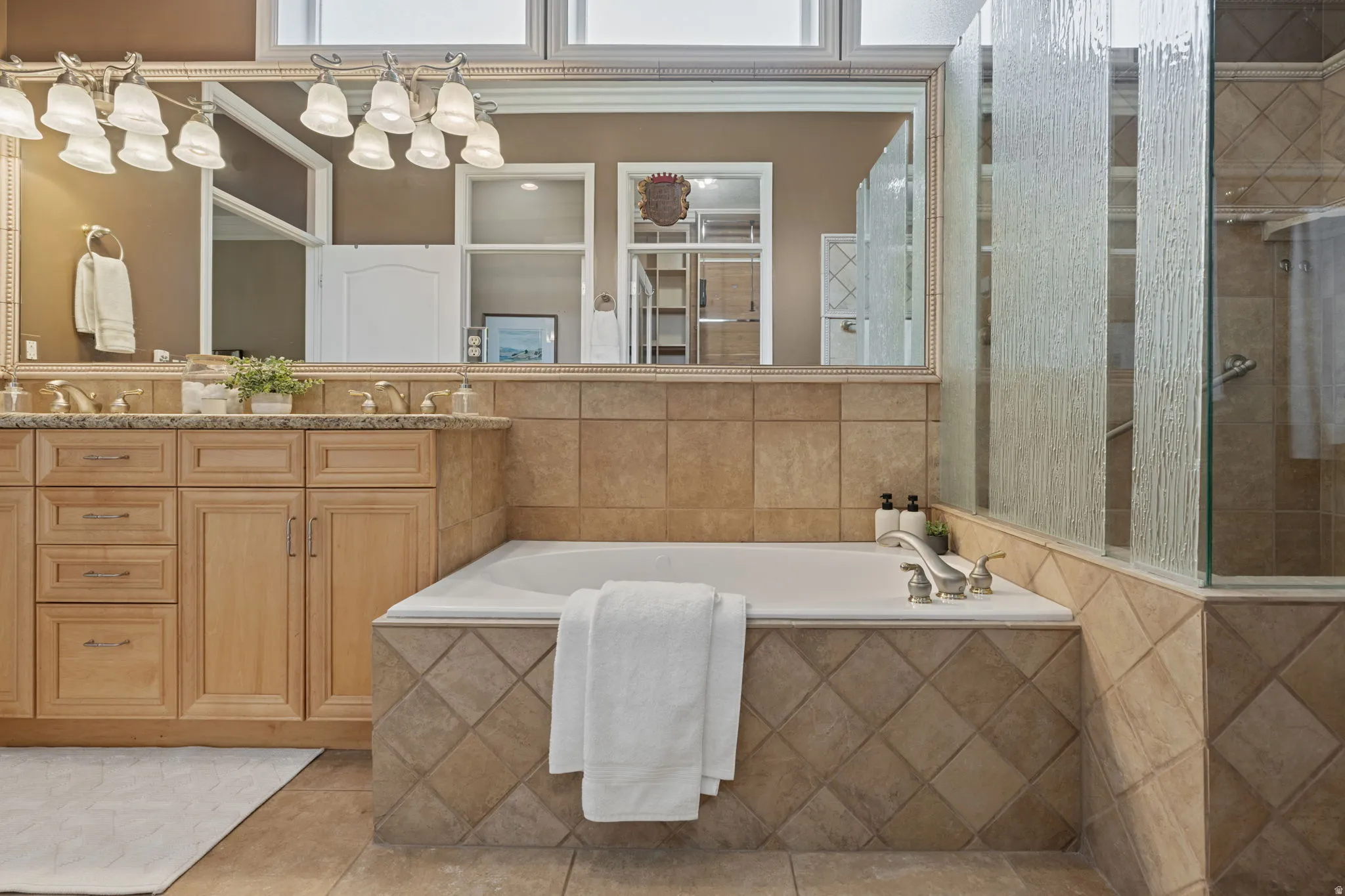 Bathroom with a jetted tub, tiled shower, vanity, and tile patterned flooring