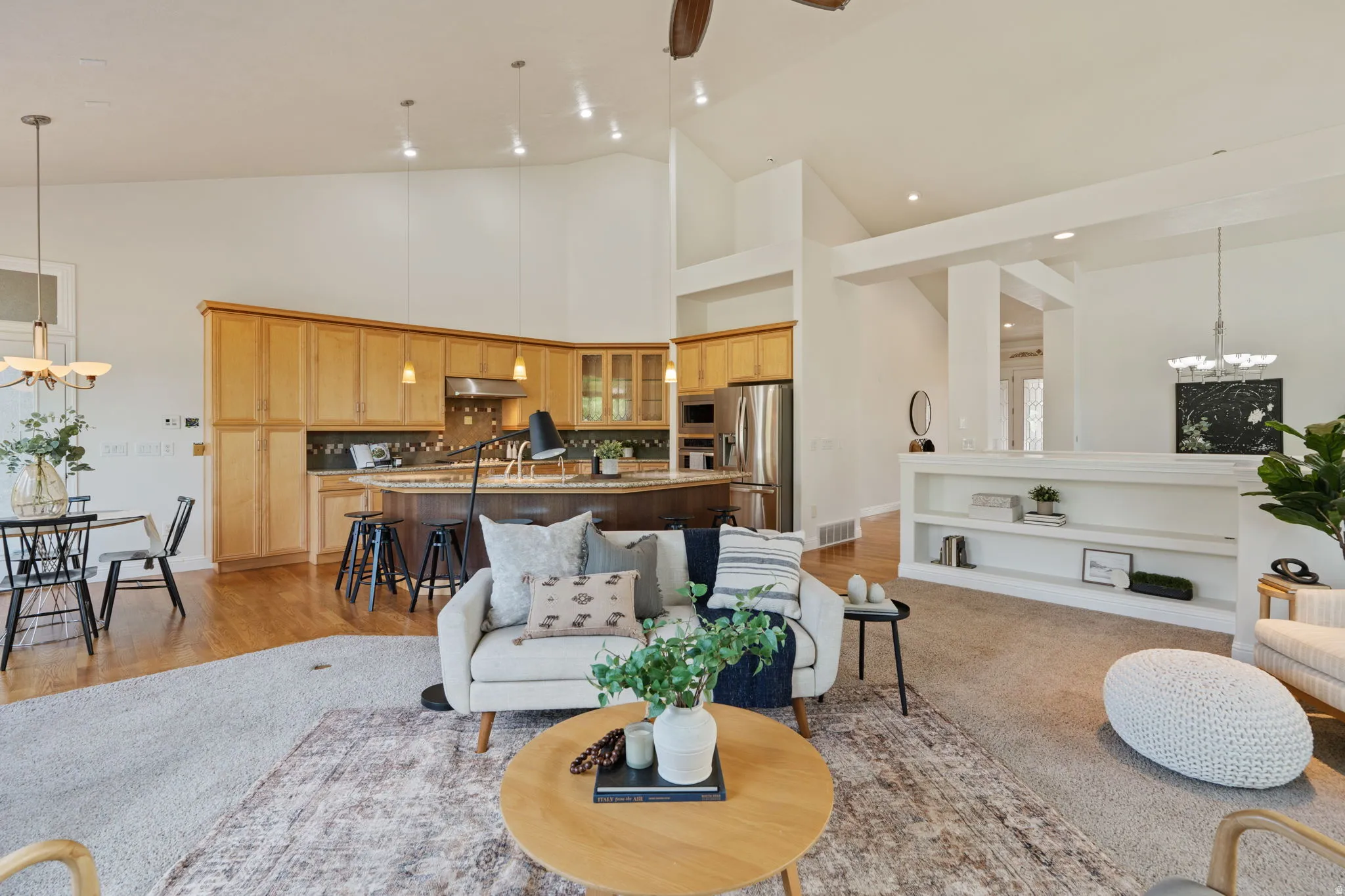 Living area featuring a chandelier, high vaulted ceiling, ceiling fan, and light wood-type flooring
