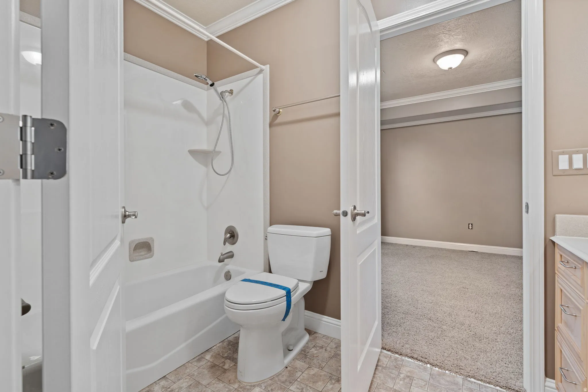 Bathroom featuring tub / shower combination, vanity, ornamental molding, light colored carpet, and a textured ceiling