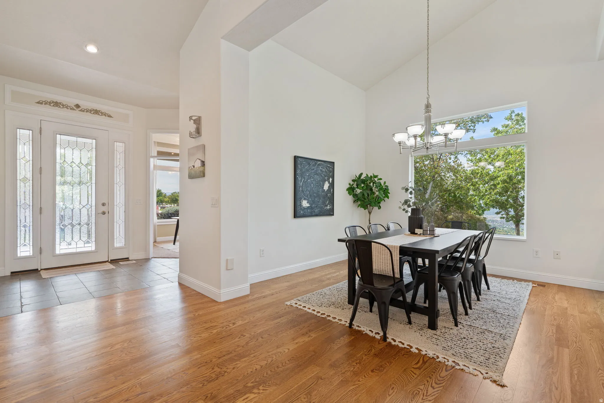Dining space with high vaulted ceiling, light wood finished floors, and a chandelier