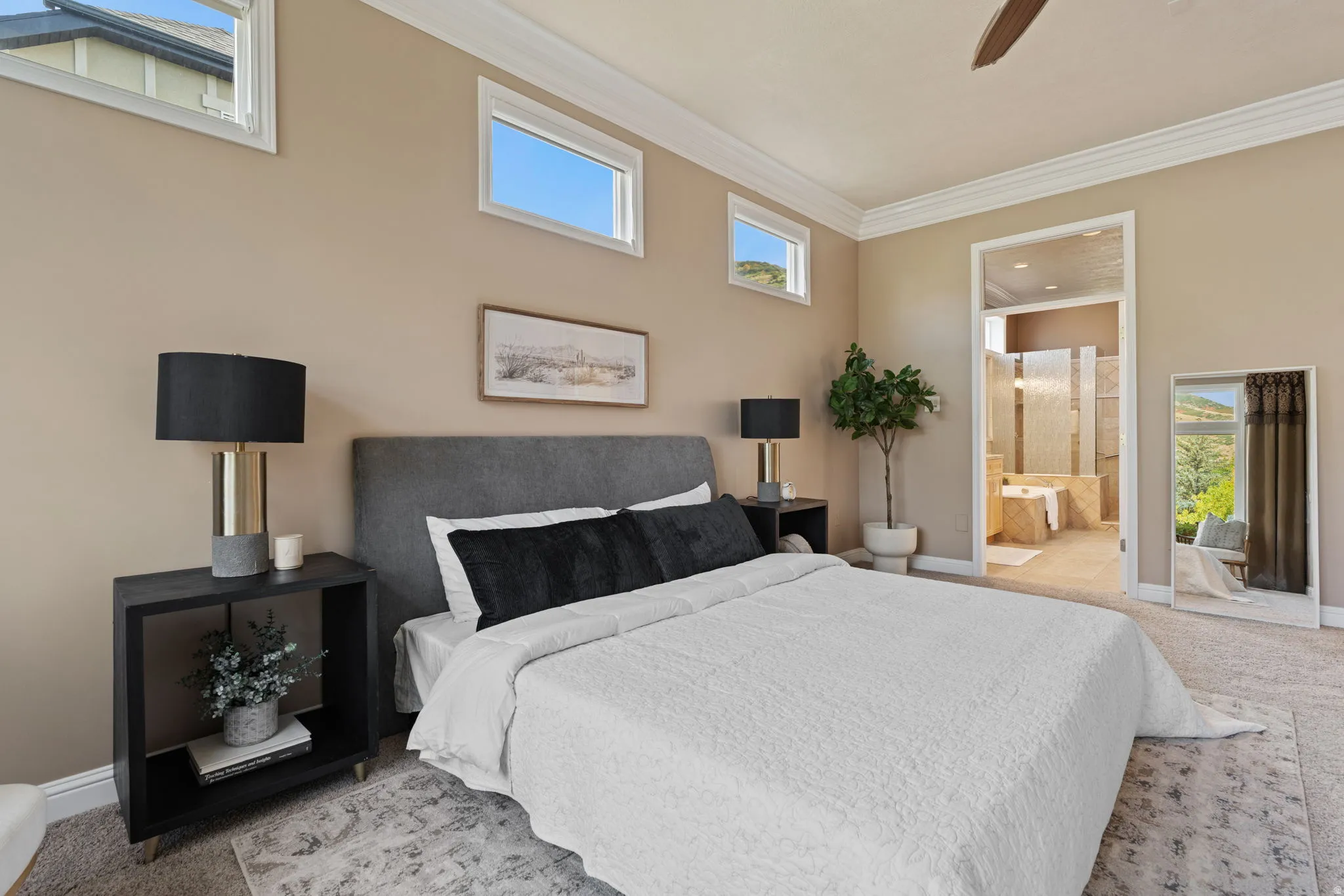 Master bedroom with connected bathroom, crown molding, and a ceiling fan