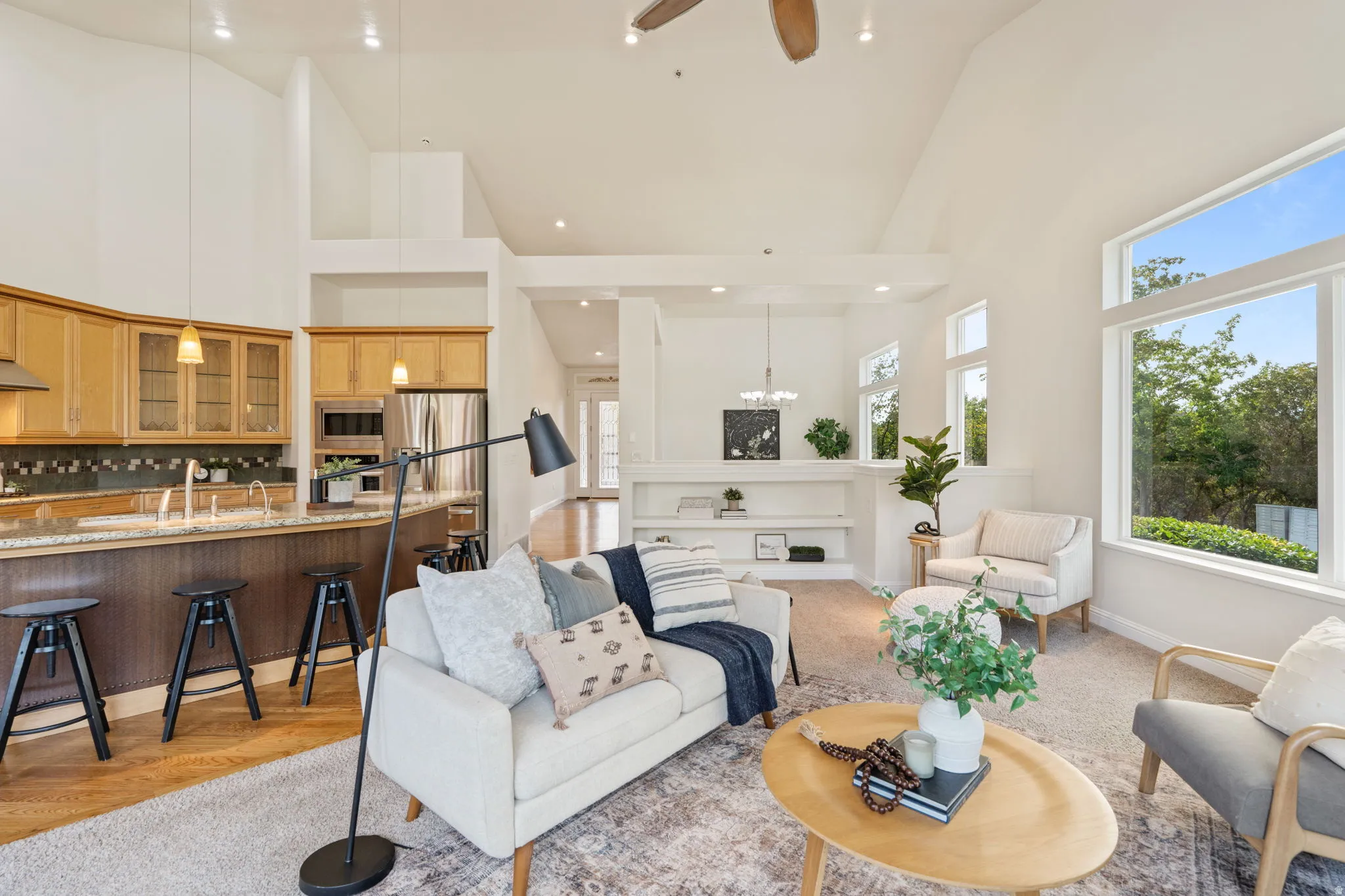 Living room featuring a high ceiling, ceiling fan, recessed lighting, and a chandelier