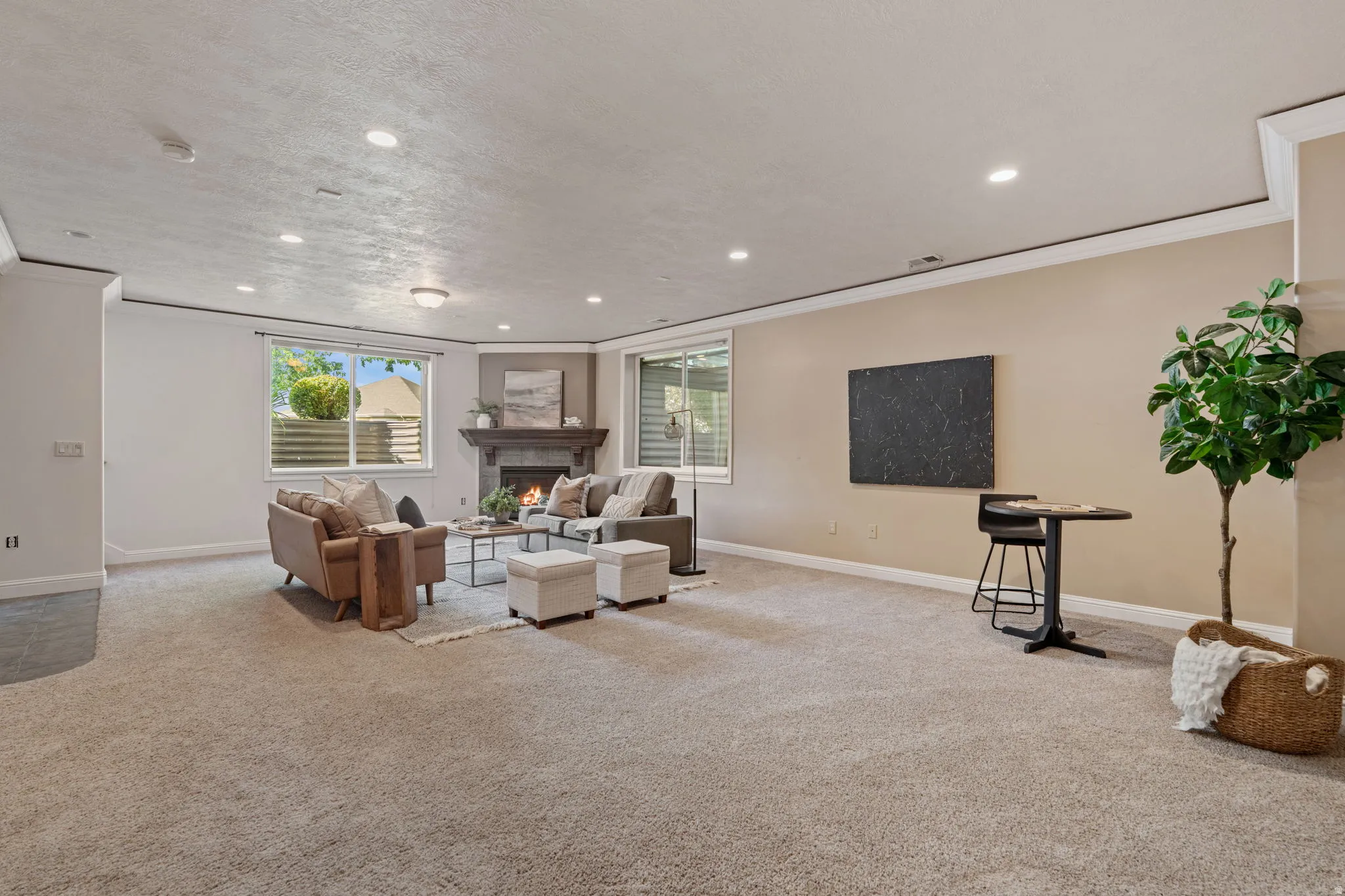 Living room featuring recessed lighting, carpet floors, a warm lit fireplace, plenty of natural light, and crown molding