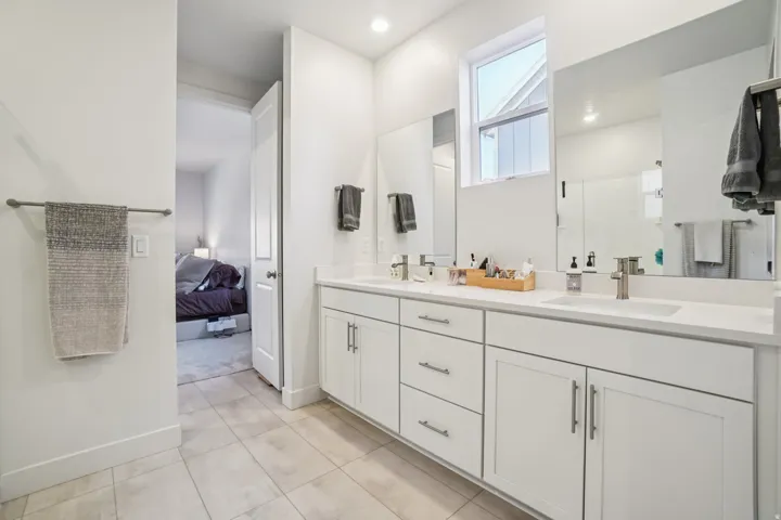 Ensuite bathroom with double vanity, a shower stall, and light tile patterned floors