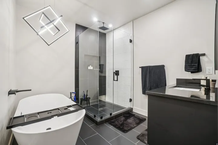Bathroom with a soaking tub, double vanity, a shower stall, dark tile patterned floors, and recessed lighting