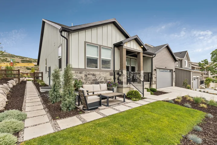 View of front facade with an outdoor hangout area, a front lawn, stone siding, board and batten siding, and concrete driveway