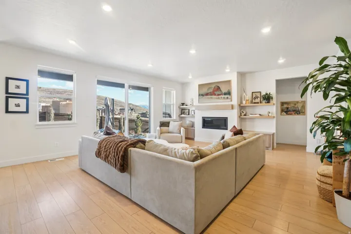 Living area with light wood-type flooring, a glass covered fireplace, built in shelves, recessed lighting, and a textured ceiling