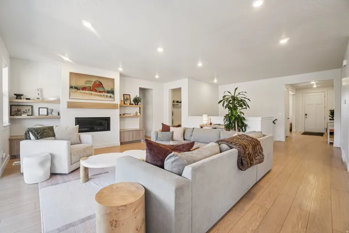 Living area with light wood-style floors, a glass covered fireplace, and recessed lighting